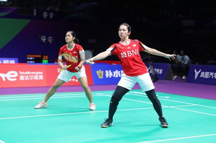 Badminton player reaching for a shot during a match rally