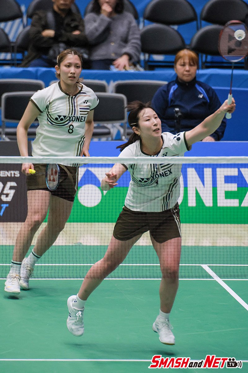 Badminton players in a fast doubles rally at the net