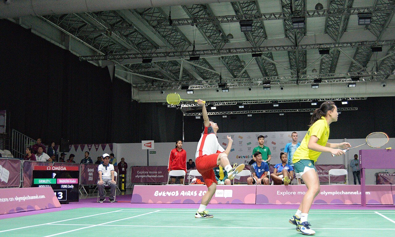 Badminton players contesting a fast rally during a mixed team match
