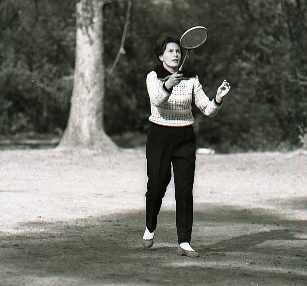 Player mid-rally on an indoor badminton court
