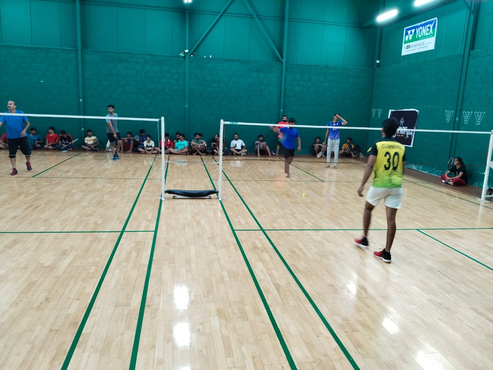 Players on an indoor badminton court during a tournament match