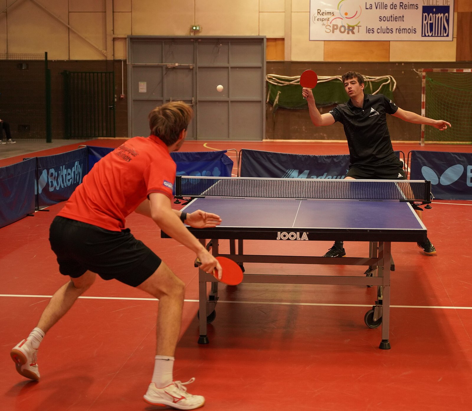 Club players contesting a table tennis rally at a club match in France