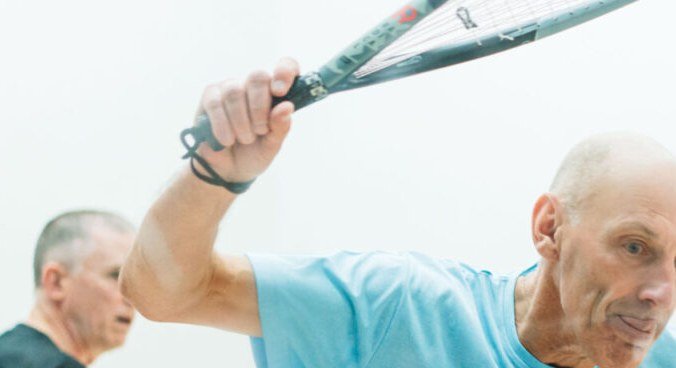 Close-up of a squash player's hand gripping the racket handle in the handshake grip during a match