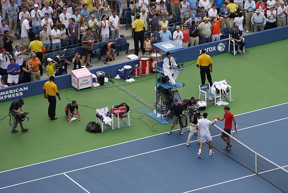 Two professional players contesting a rally on an outdoor hard court