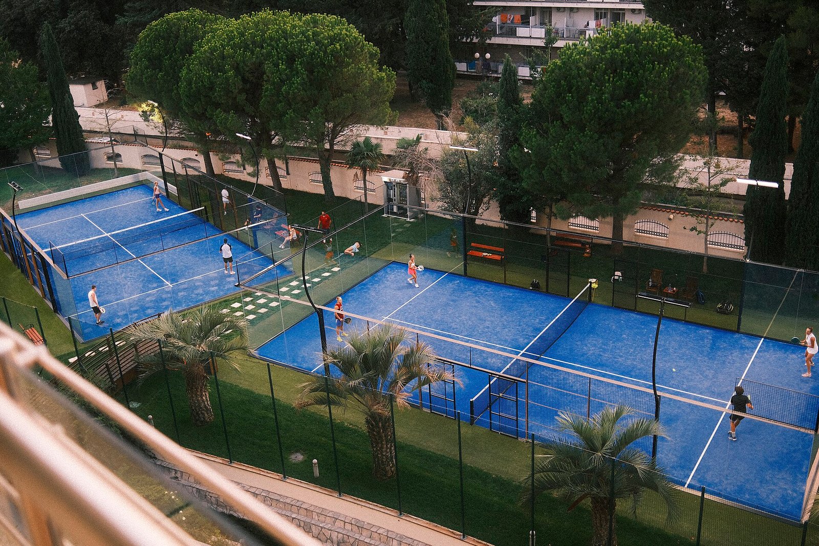 Padel players contesting a doubles rally on outdoor blue courts