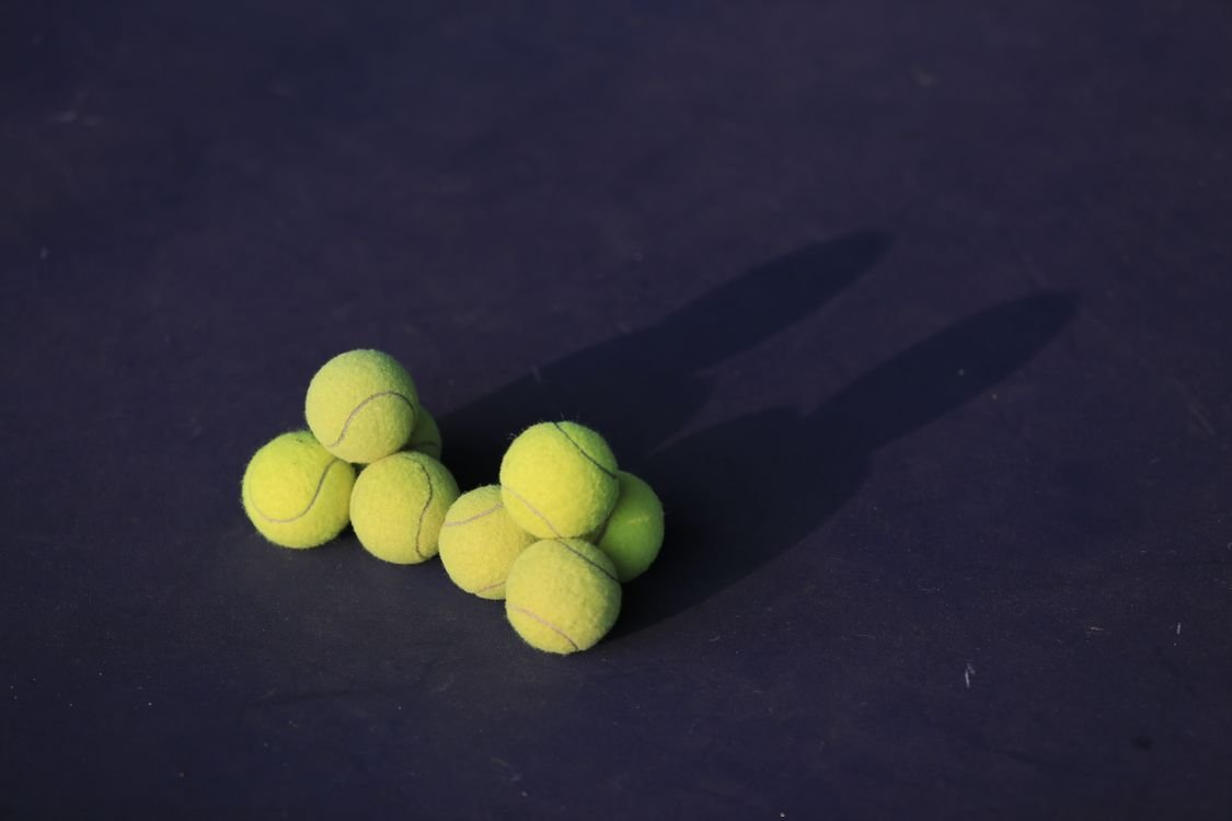 A cluster of tennis balls gathered on a court during practice
