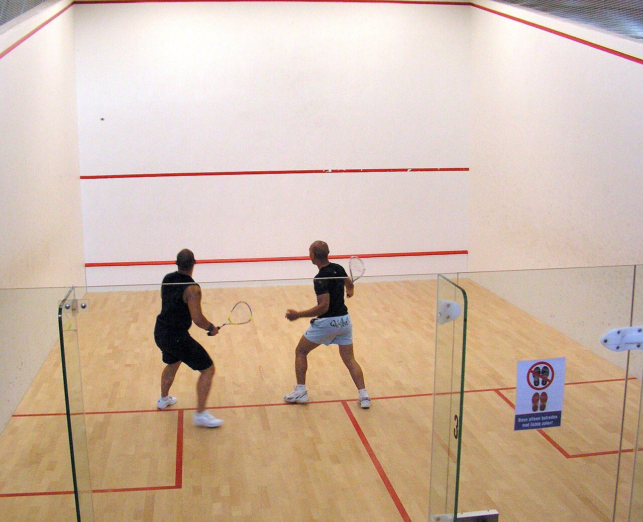 A squash court with wooden floor and marked walls ready for play