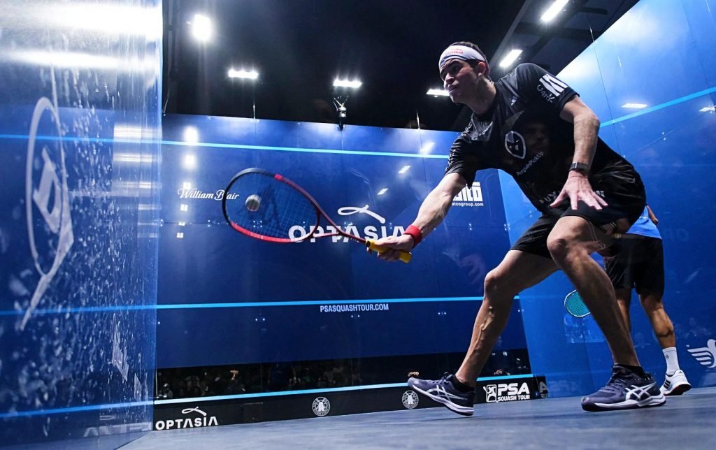 Squash player driving the ball down the side wall during a rally