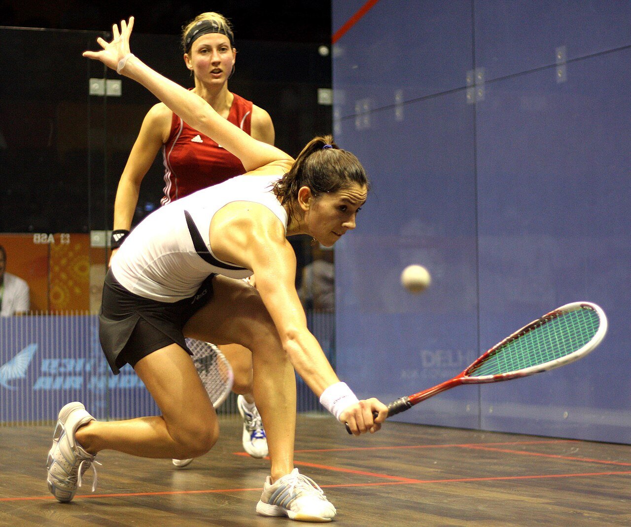 Advanced squash player stretched into a deep forehand lunge during a professional match