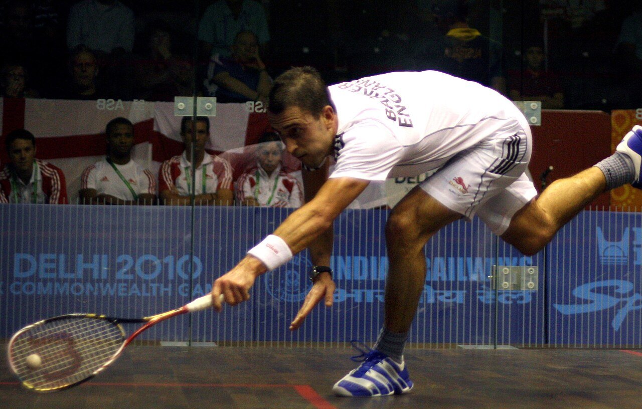 Advanced squash players contesting a rally at full stretch during a professional match
