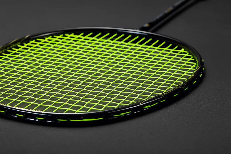 Close-up of a badminton racket string bed with bright green strings against the black frame