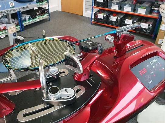 Badminton racket mounted on an electronic stringing machine set to 26.0 lbs during a restring