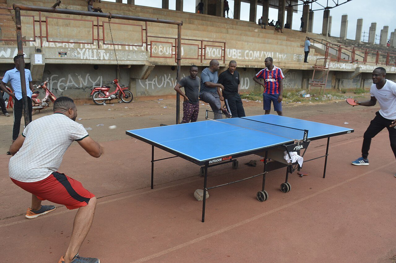 Students playing table tennis outdoors at a school stadium