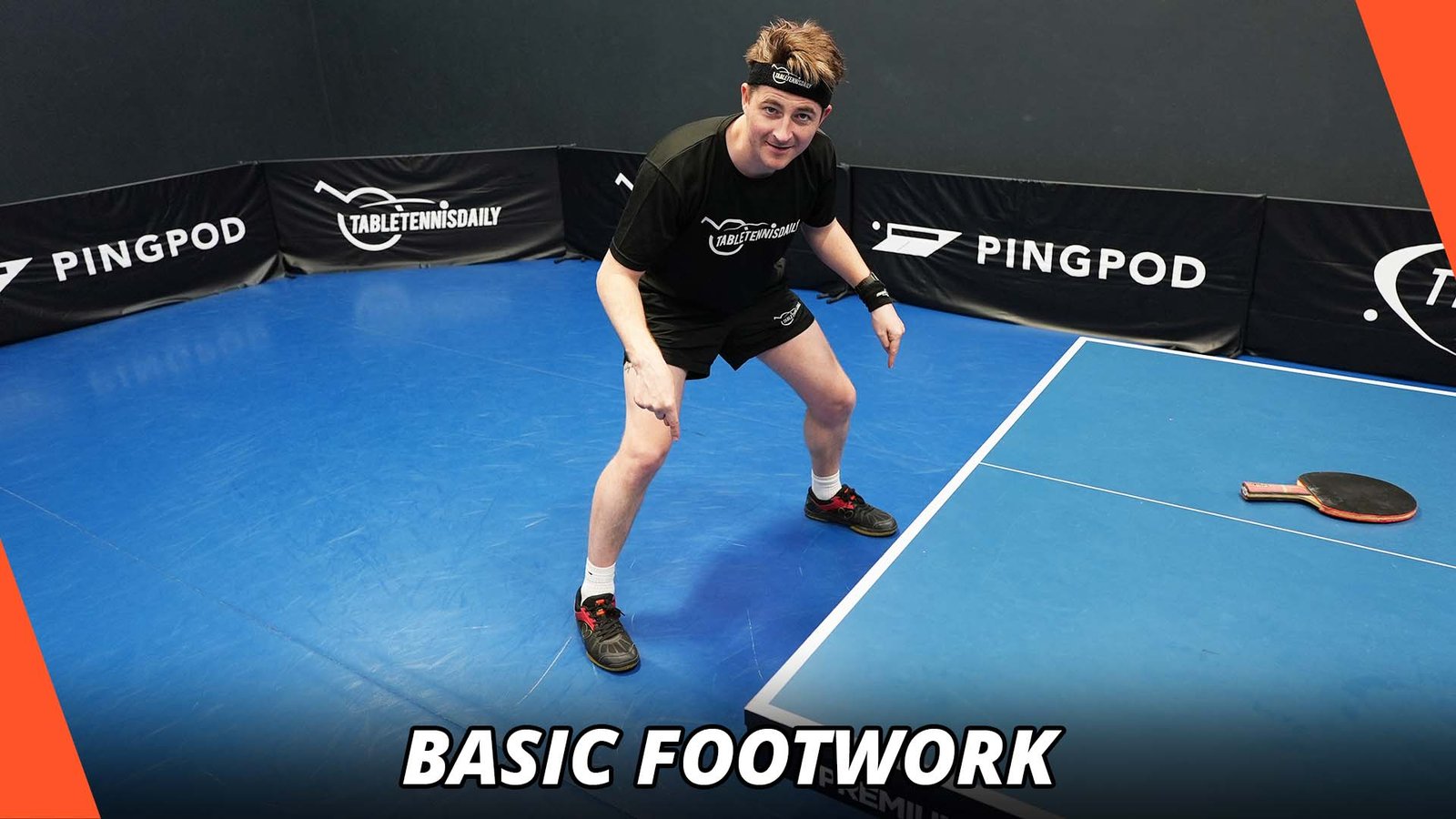 Table tennis player practising lateral footwork drills beside the table during training