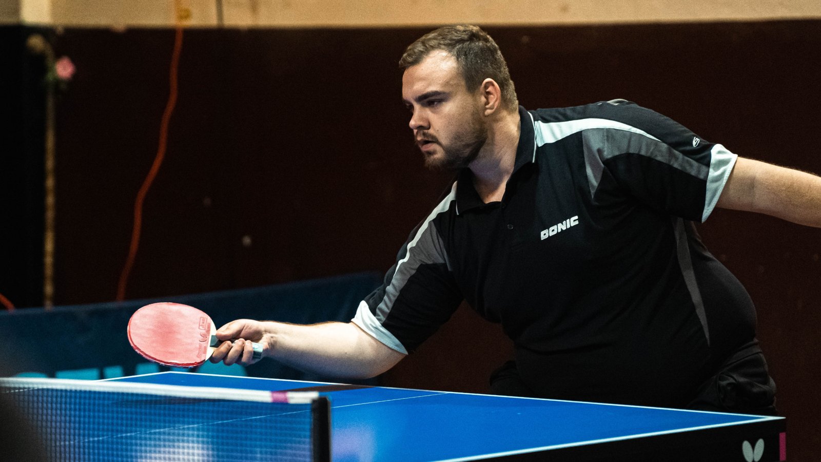 Table tennis player stretched wide in a rally during a competitive match