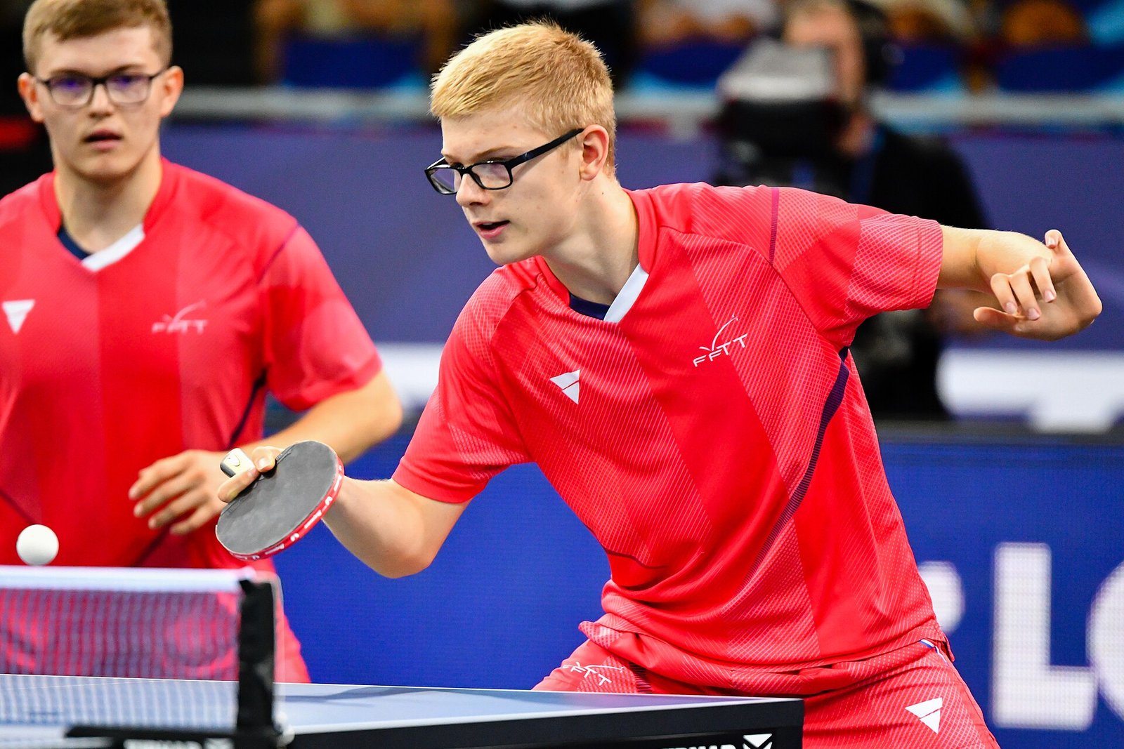 Professional table tennis player stretched wide in a forehand lunge during a European Championships match