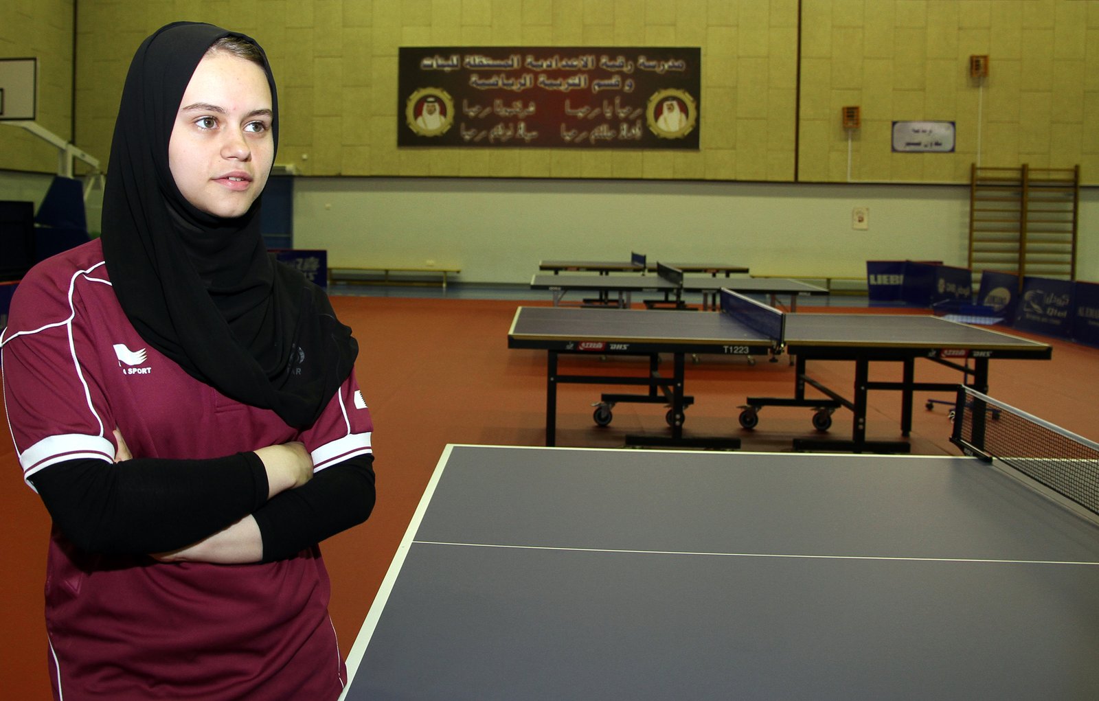 Table tennis player stretched wide in a rally, weight over the front foot close to the table