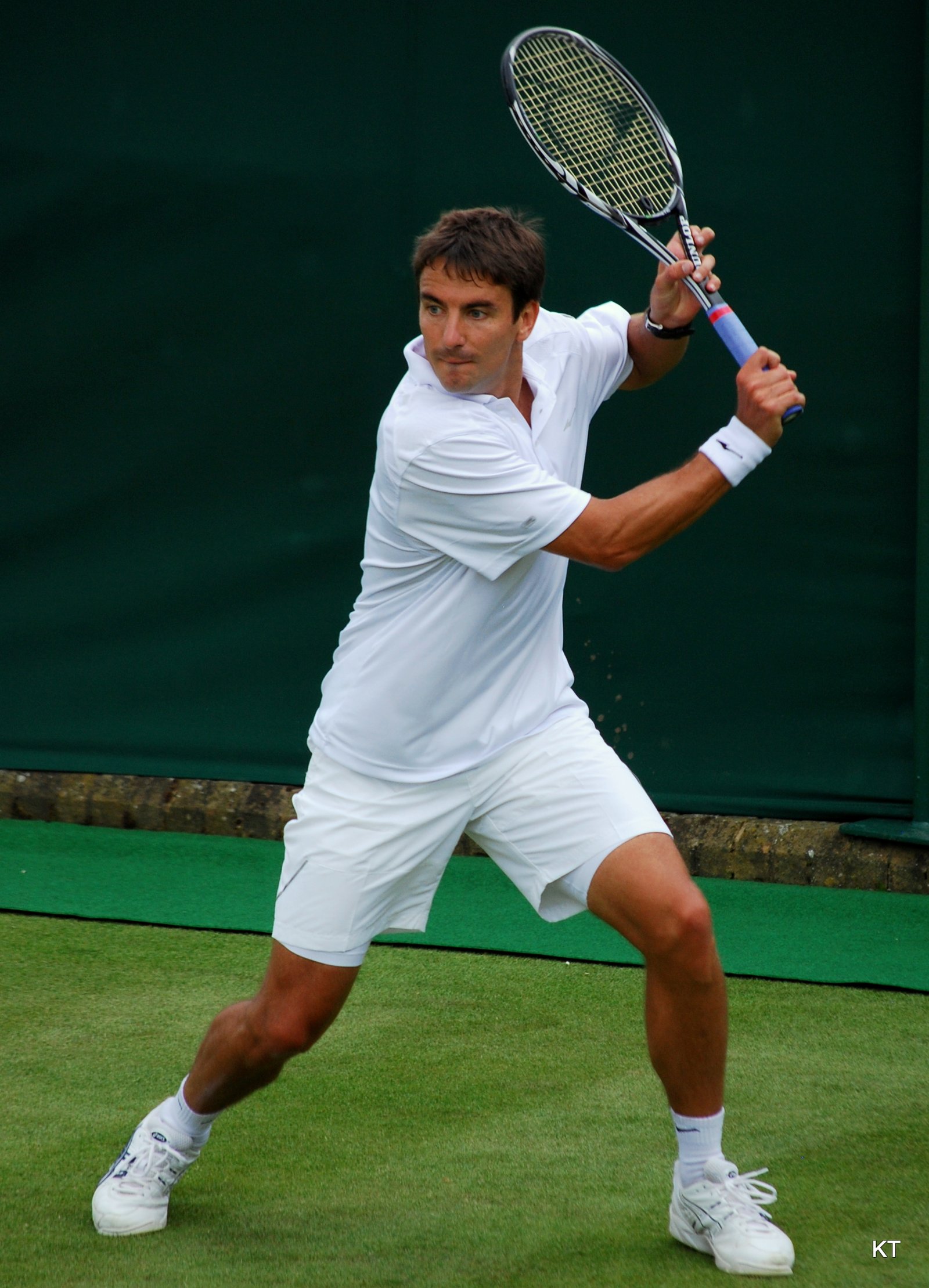 Tennis player hitting a backhand during a match, racket extended through the stroke