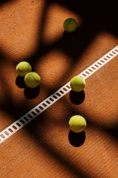 A tennis ball resting on a clay court surface