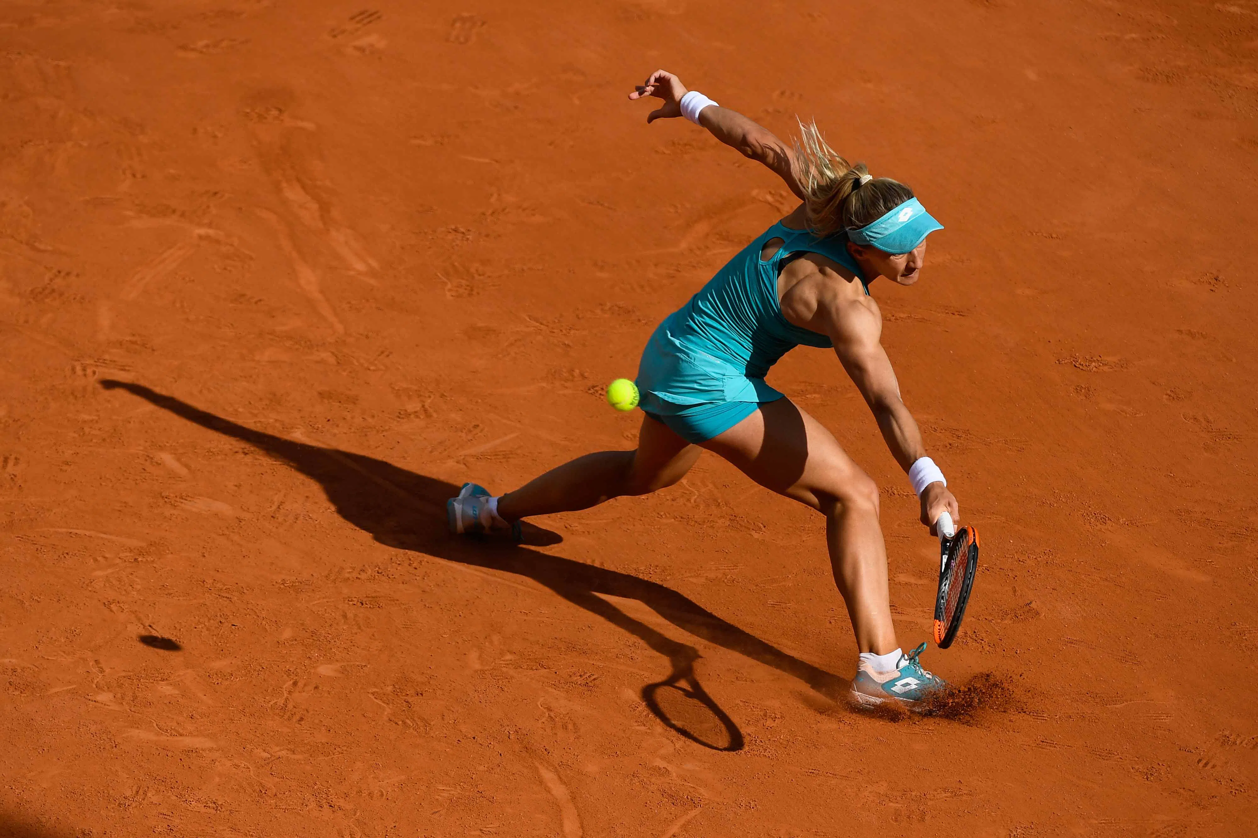 Player sliding into a shot on a clay tennis court