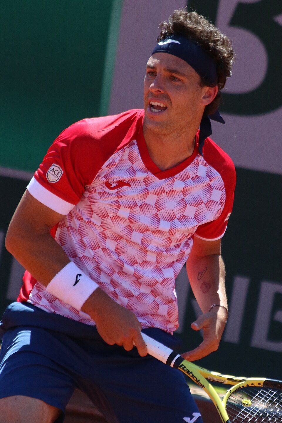 Tennis player sliding into a shot on a clay court at Roland Garros