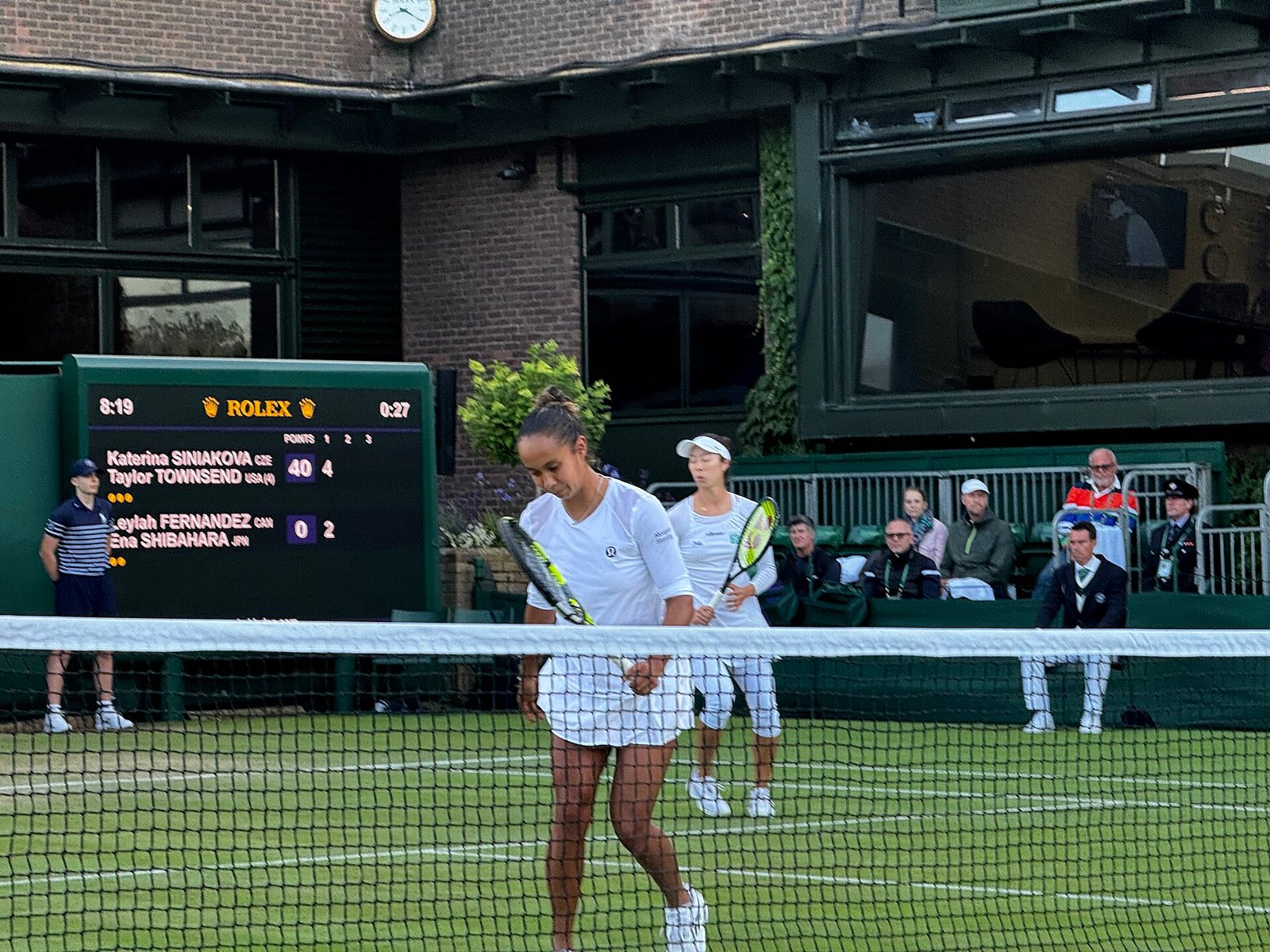 Doubles players at the net during a tennis match, rackets up for the volley exchange