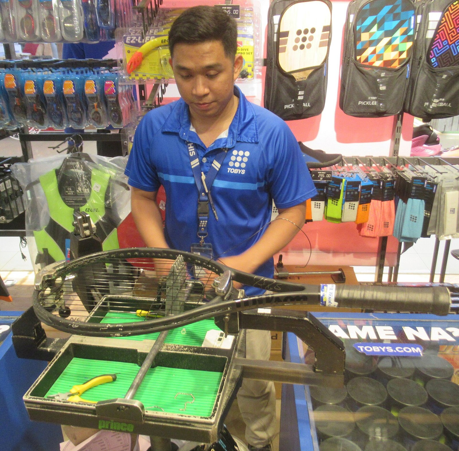 Tennis racket mounted on a stringing machine while a fresh string bed is woven