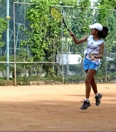 A woman tennis player driving a forehand during a club match