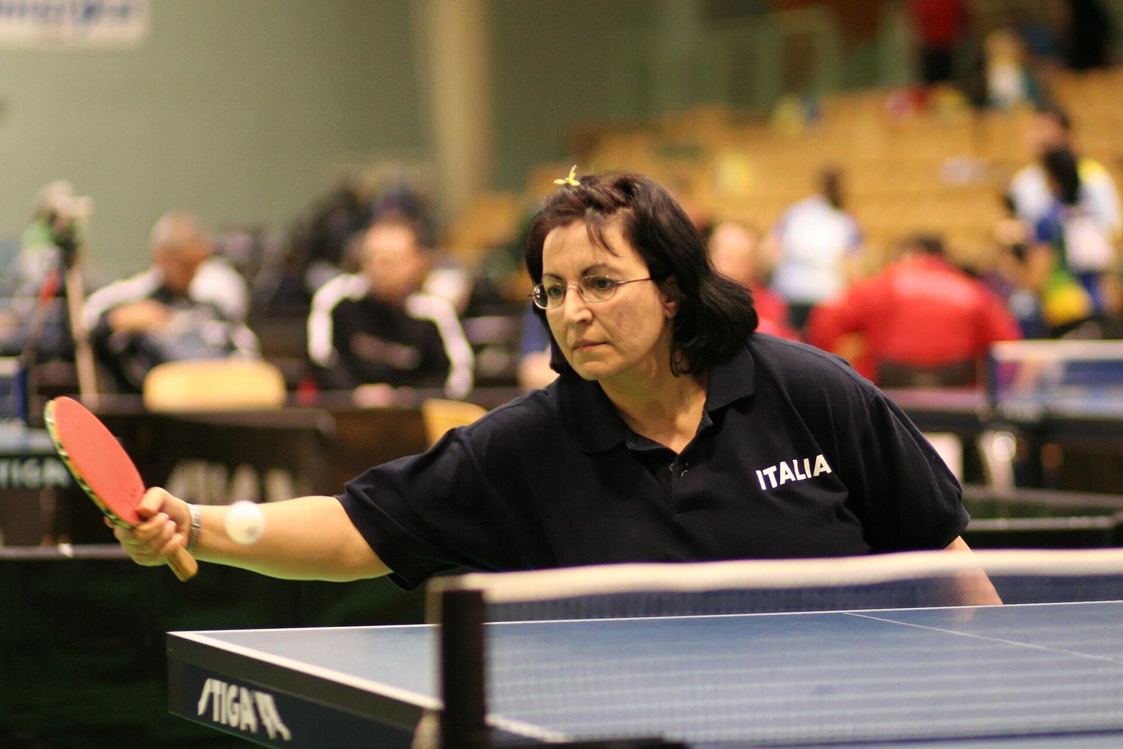 Women's table tennis player mid-rally at the table in a low ready stance