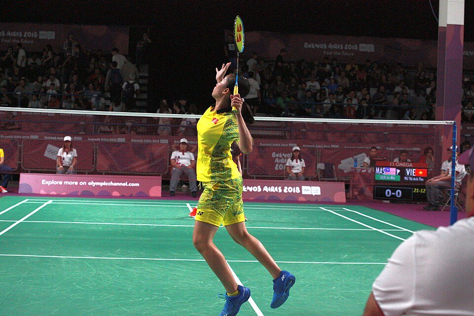 Junior player lunging at the net during a youth badminton match