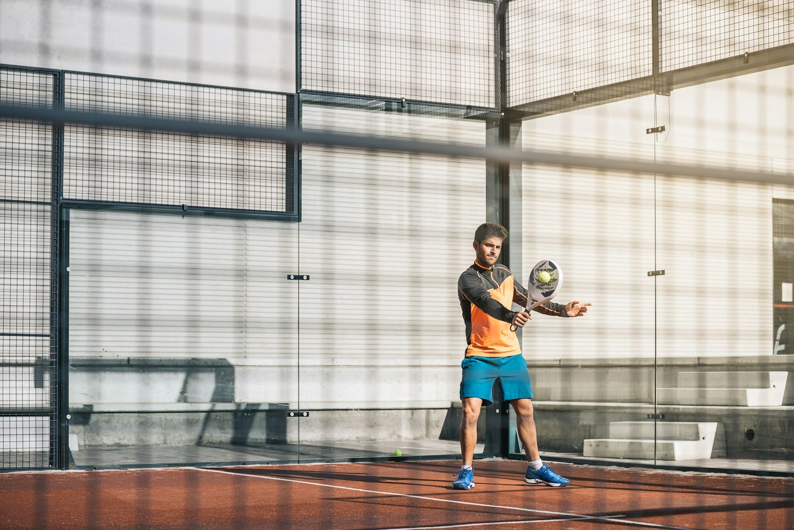 Club player mid-rally on an indoor padel court — technique, not equipment, is still the deciding factor at this stage