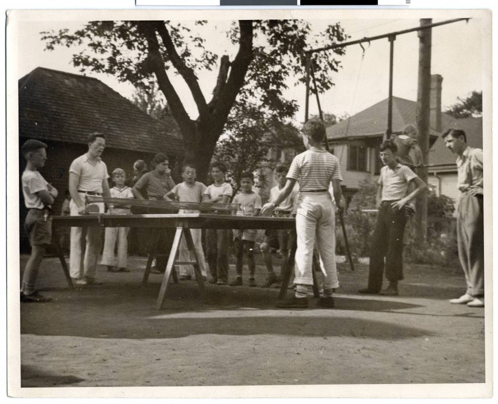 Casual outdoor table tennis match being played on a park table in the open air