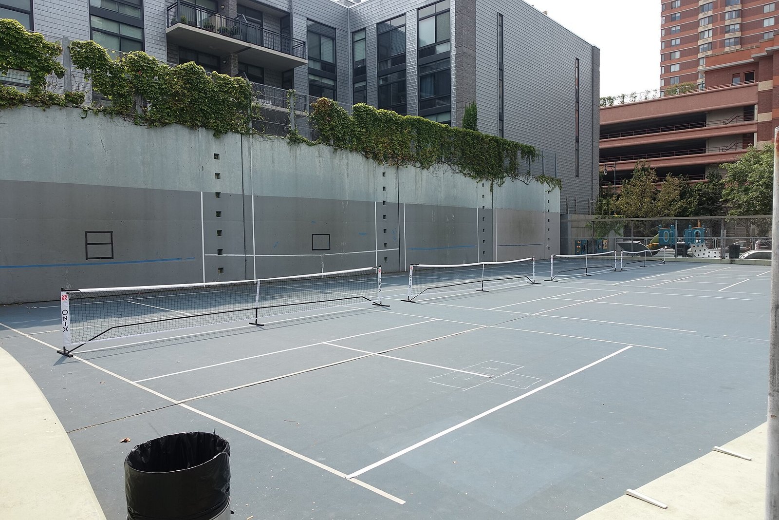 Portable-net pickleball courts lined out on an outdoor hard court in a city park