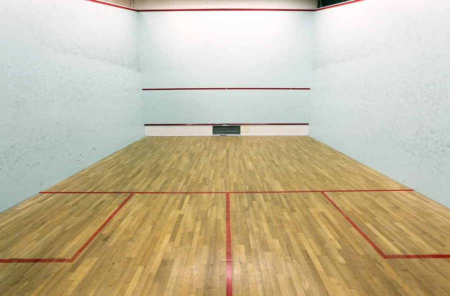 An empty squash court showing the red lines: the tin and service line on the front wall, the short line, half-court line and service boxes on the floor