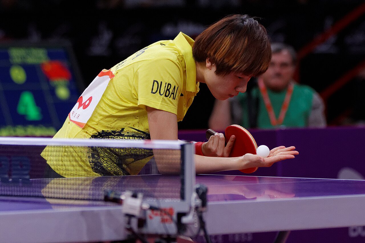 A server holding the ball flat on an open palm before the toss, racket poised — the starting position every legal service must begin from