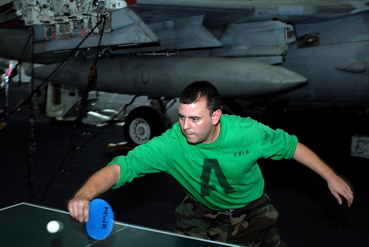 A player playing a forehand return during a rally, racket meeting the ball after its bounce on his side of the table