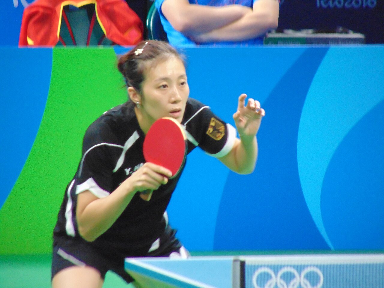 Table tennis player in a low ready position close to the table, knees bent and racket held up in front of the body, waiting to receive at the Rio 2016 Olympics