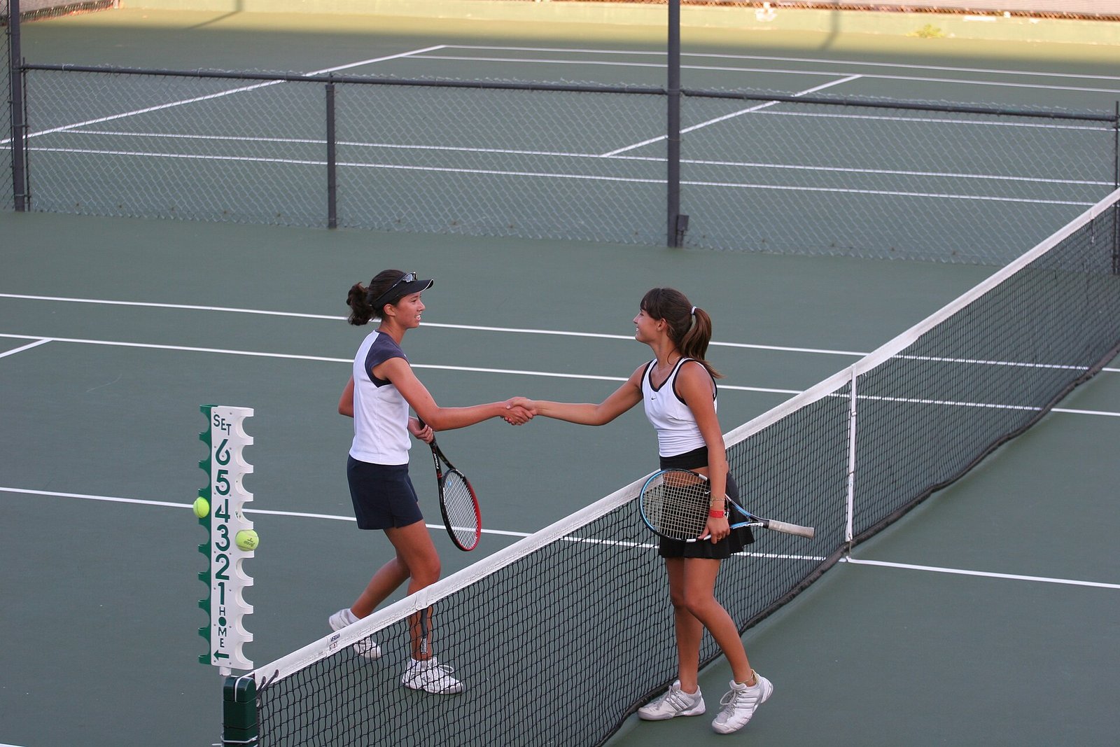 Two tennis players shaking hands at the net after a match